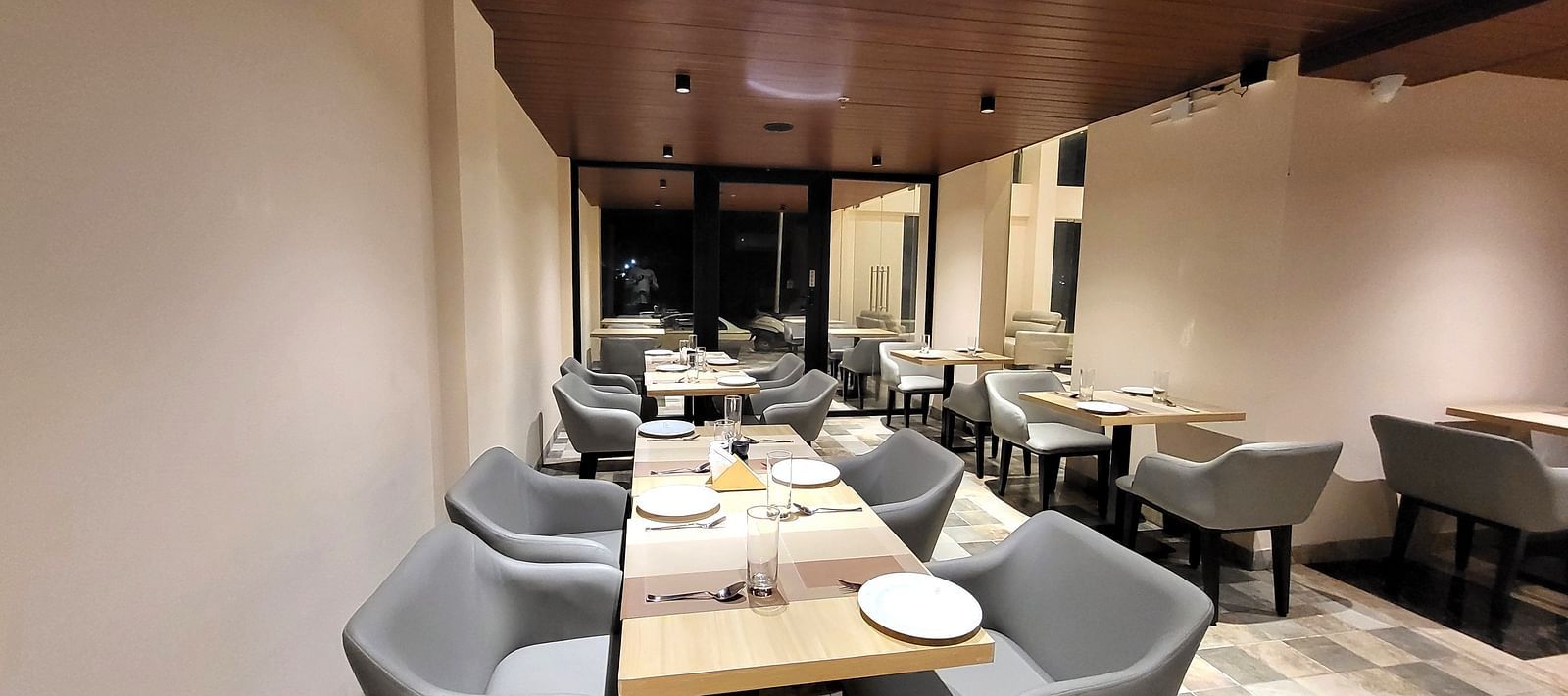 Grey chairs and tables set in a row in 6ix Sea View Restaurant at 6ix Seashore Hotel, Port Blair