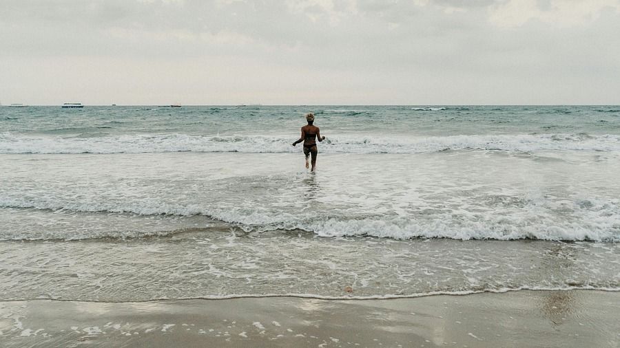 A person running towards the ocean on a cloudy day