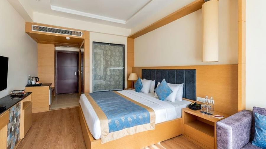 Superior Hotel room with bed, wardrobe, television, and seating at Golden Tulip, Udaipur.