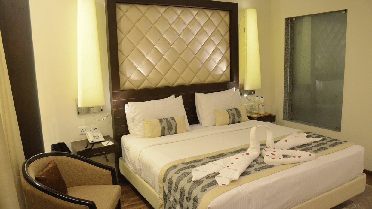  An elegant bedroom with a decorated bed, cushioned headboard, and warm lighting in a luxury hotel in Lucknow - Clarks Avadh, Lucknow