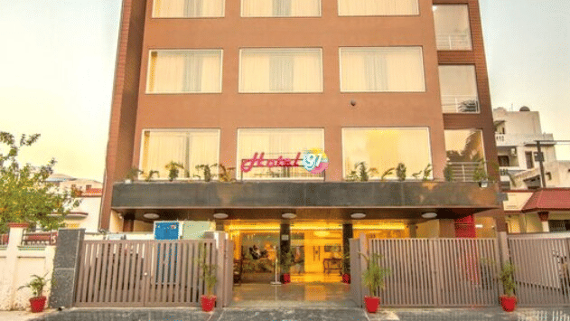 An exterior front view of Hotel 91 HUDA Premier, Gurugram building with signage, entrance area, and boundary wall.