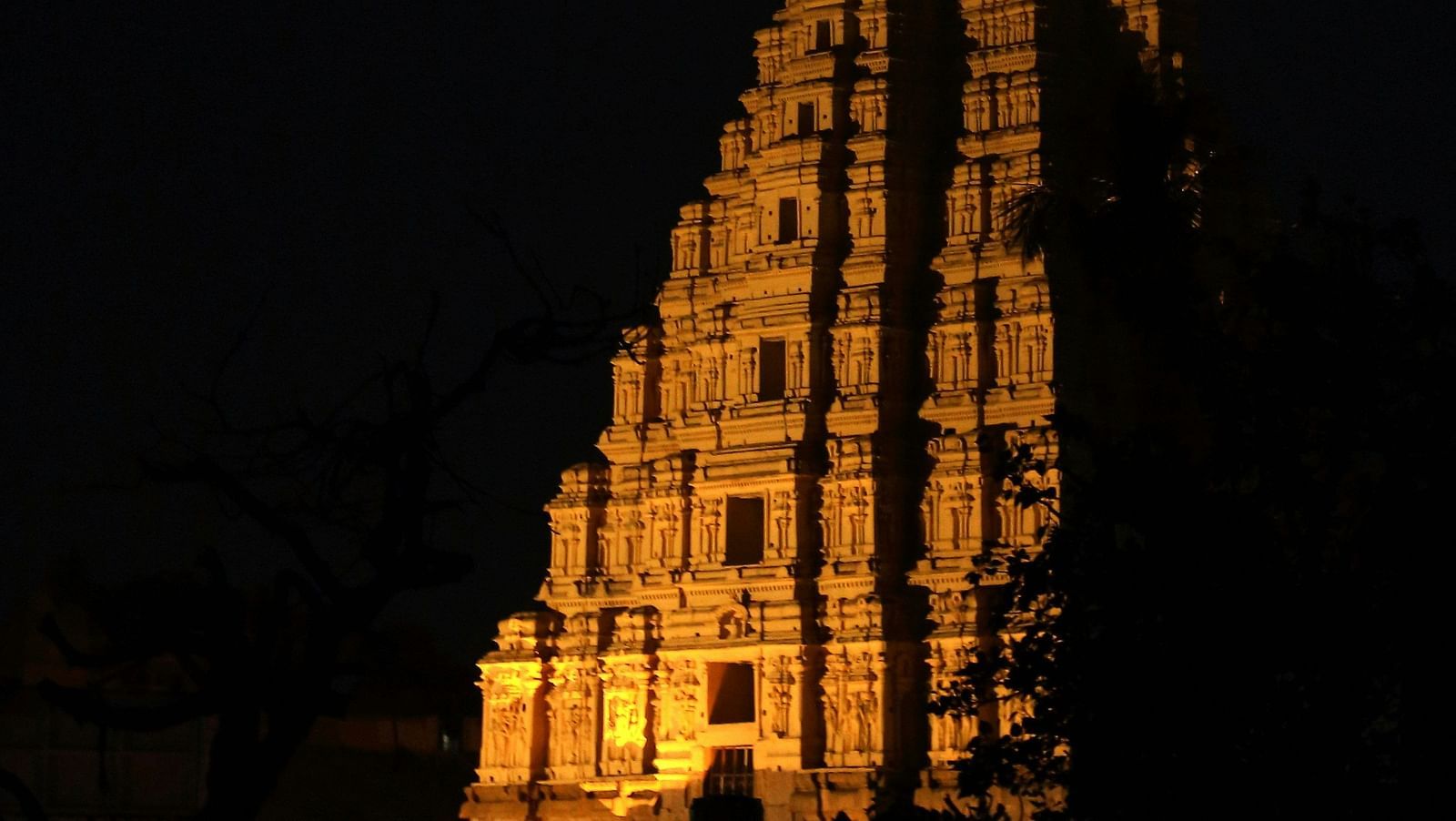 Illuminated temple tower glowing against the dark night sky.