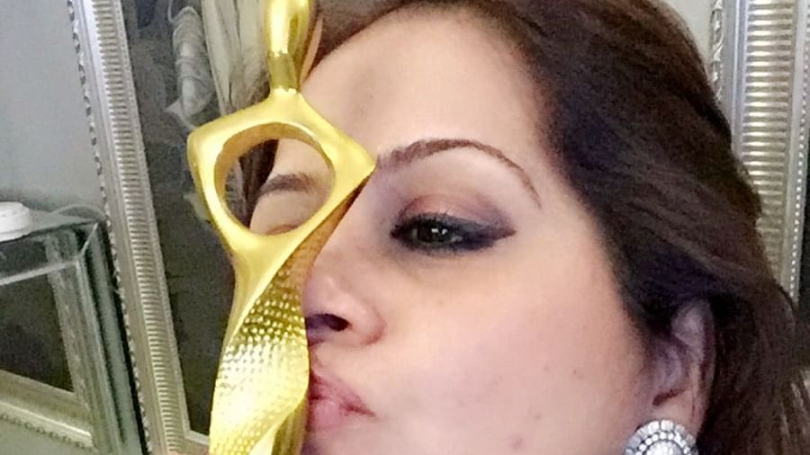 Kiran Bawa kissing an award while posing for a picture - IOSIS Spa & Wellness