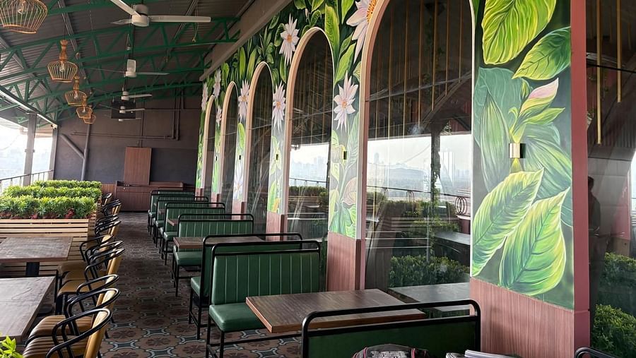 A dining area with green booth seating and large arched windows featuring decorative murals - Melior Inn