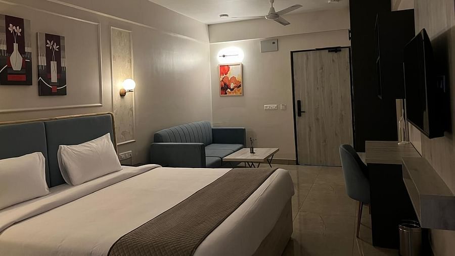 A spacious room side view featuring a large bed, furniture, a table placed against the wall, and a ceiling fan 