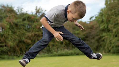 A boy jumping on a trampoline outdoors at the best resort in Bangalore.