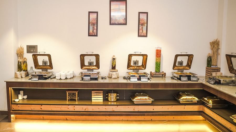 Buffet setup with food warmers, decorative elements, and vibrant artwork on the wall - Shervani Pebbles & Pines, Corbett