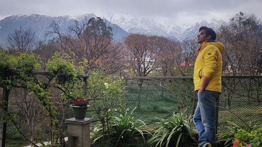 Scenic view of green hills and snow-capped mountains from a high point.