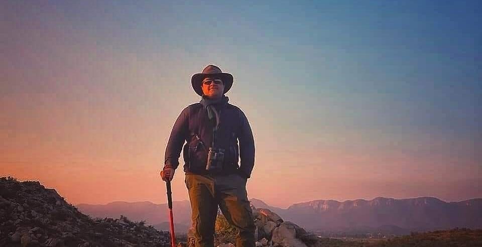 An image of a person standing on a hilltop with a dusky sky as the backdrop