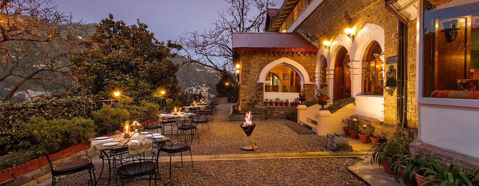 An image of naini retreat, nainital, with a scenic view of  building with a stone exterior and arched doorways. The building is illuminated by warm lights, creating a cozy atmosphere. 