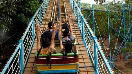 A group of people ascending on a roller coaster with railings on the side at Water Kingdom - one of the Fun Places in Mumbai.