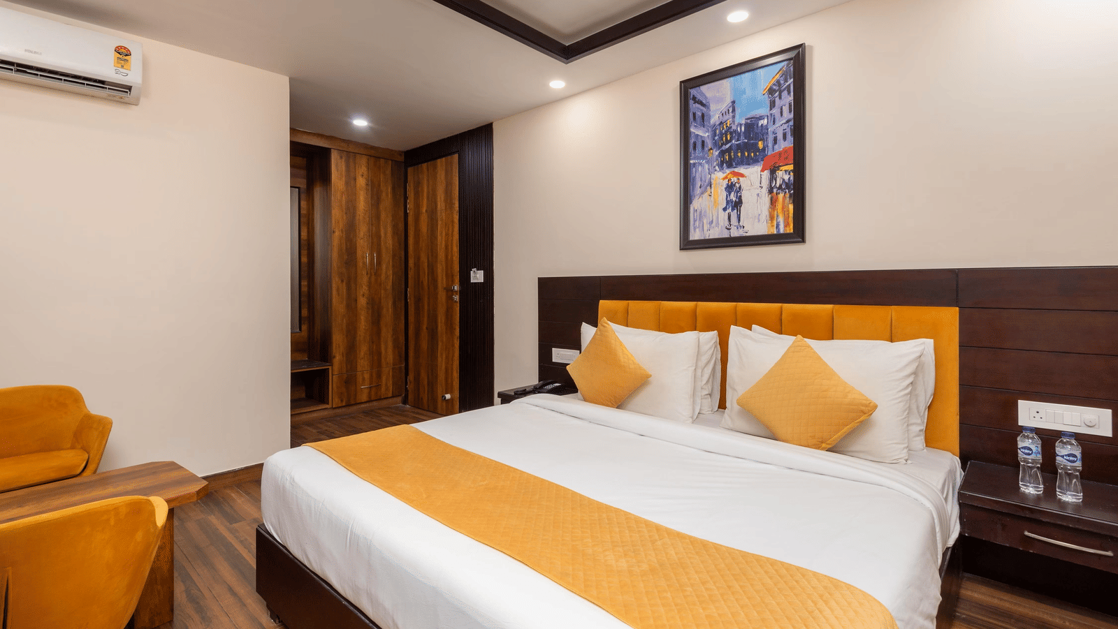 A large bed with pillows, a bedside table, and a framed picture hanging on the wall at Perfectstayz Premium Shanti Heritage, Haridwar