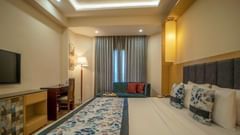 View of a Premium hotel room with patterned bedding and television at Golden Tulip, Udaipur.