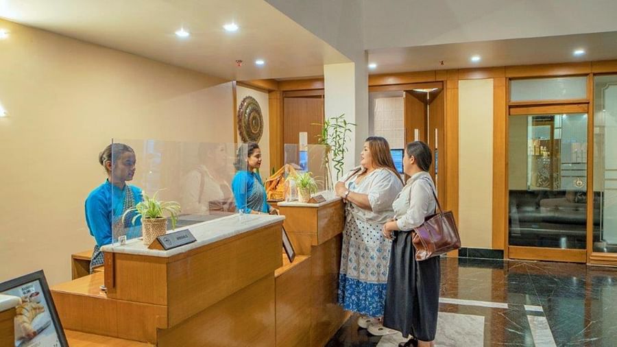 Reception area with two guests and staff during check-in at Golden Tulip, Udaipur.