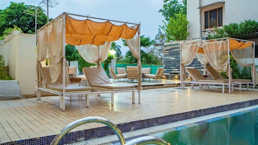 Deck area with lounge chairs and umbrellas by the pool at Golden Tulip, Udaipur.