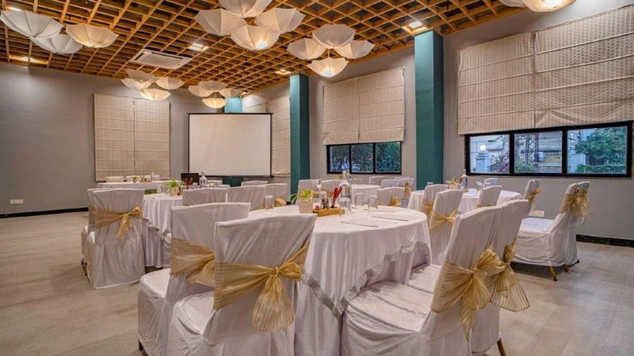 Banquet hall with round tables and white-gold chair covers at Golden Tulip, Udaipur.