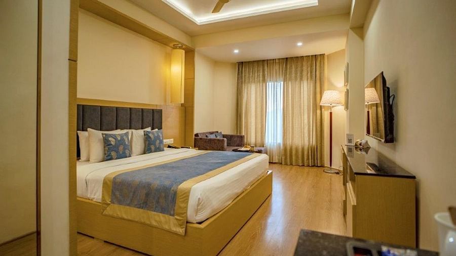 Wide-angle of a superior room with double bed and full-length curtains at Golden Tulip, Udaipur.