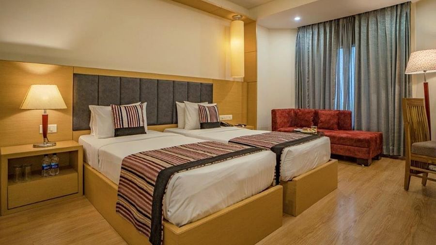 Spacious superior twin room with twin beds, armchairs, and bedside lamps at Golden Tulip, Udaipur.