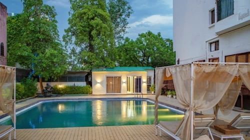 Swimming pool area with deck and cabanas at Golden Tulip, Udaipur.