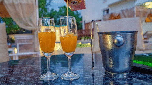 Close-up of orange drinks and ice bucket on a table near the pool at Golden Tulip, Udaipur.