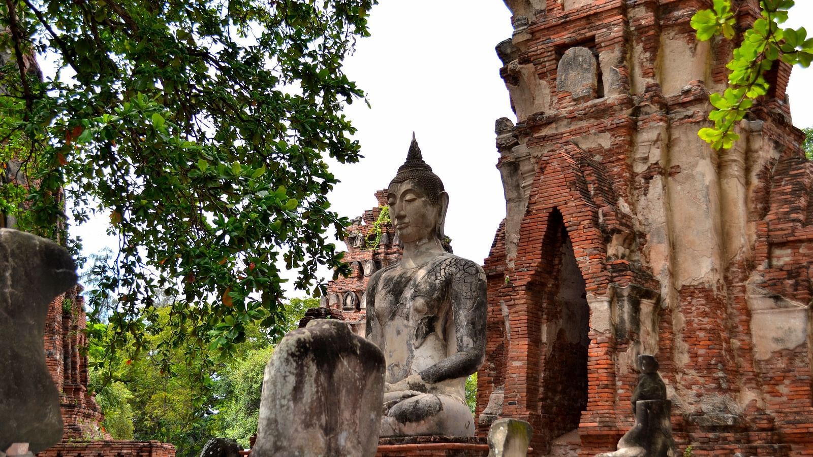 a buddha statue amogst ruins during daytime