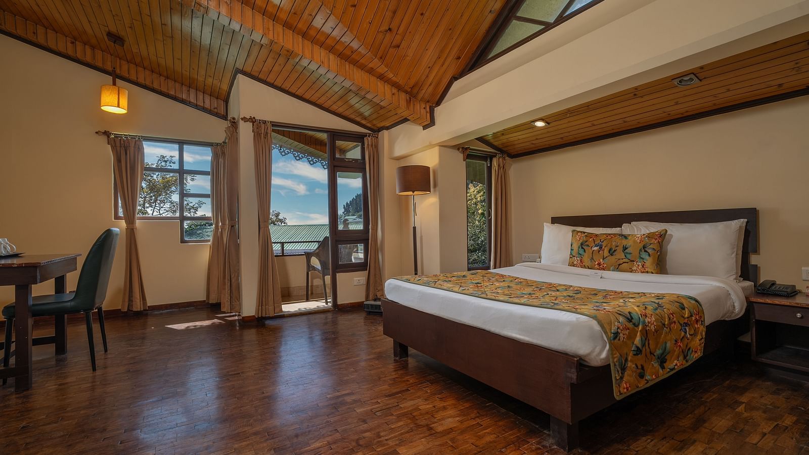 Deluxe room with a spacious bed, wooden furniture such as a bedside table, dining table, and chair at Summit Norling Resort & Spa, Gangtok