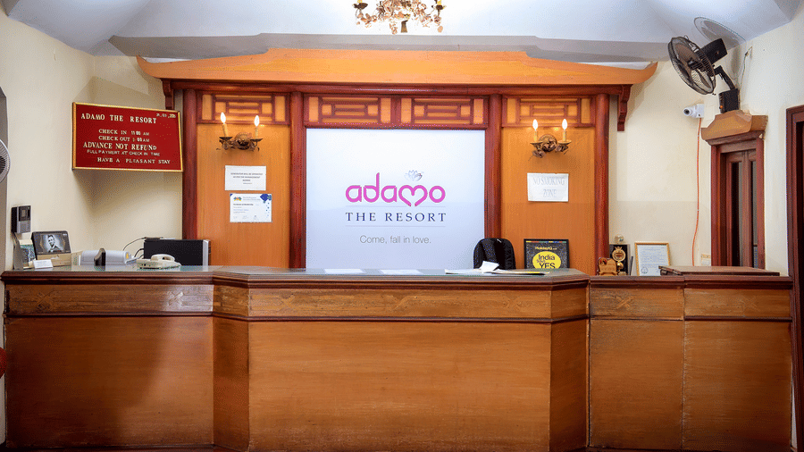 The front desk of the hotel with a long wooden table and the hotel logo on the wall behind the desk.