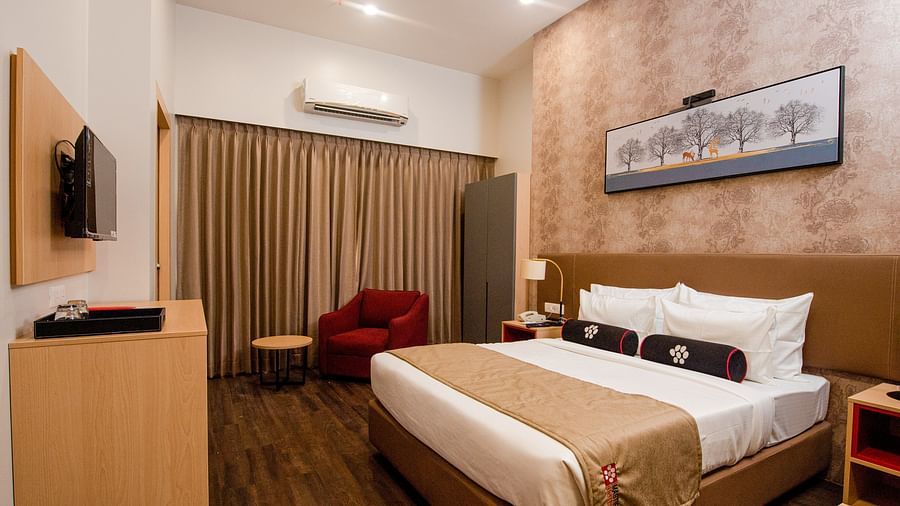 a plush bed with warm toned interiors and room amenities - Mastiff Hotel, Ankleshwar