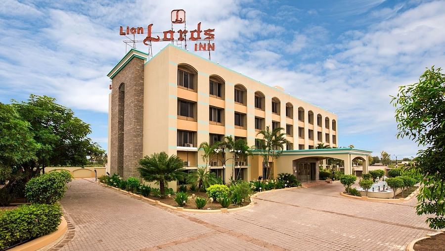 The front of a light-coloured building visible on a sunny day - Lion Lords Inn Rajula