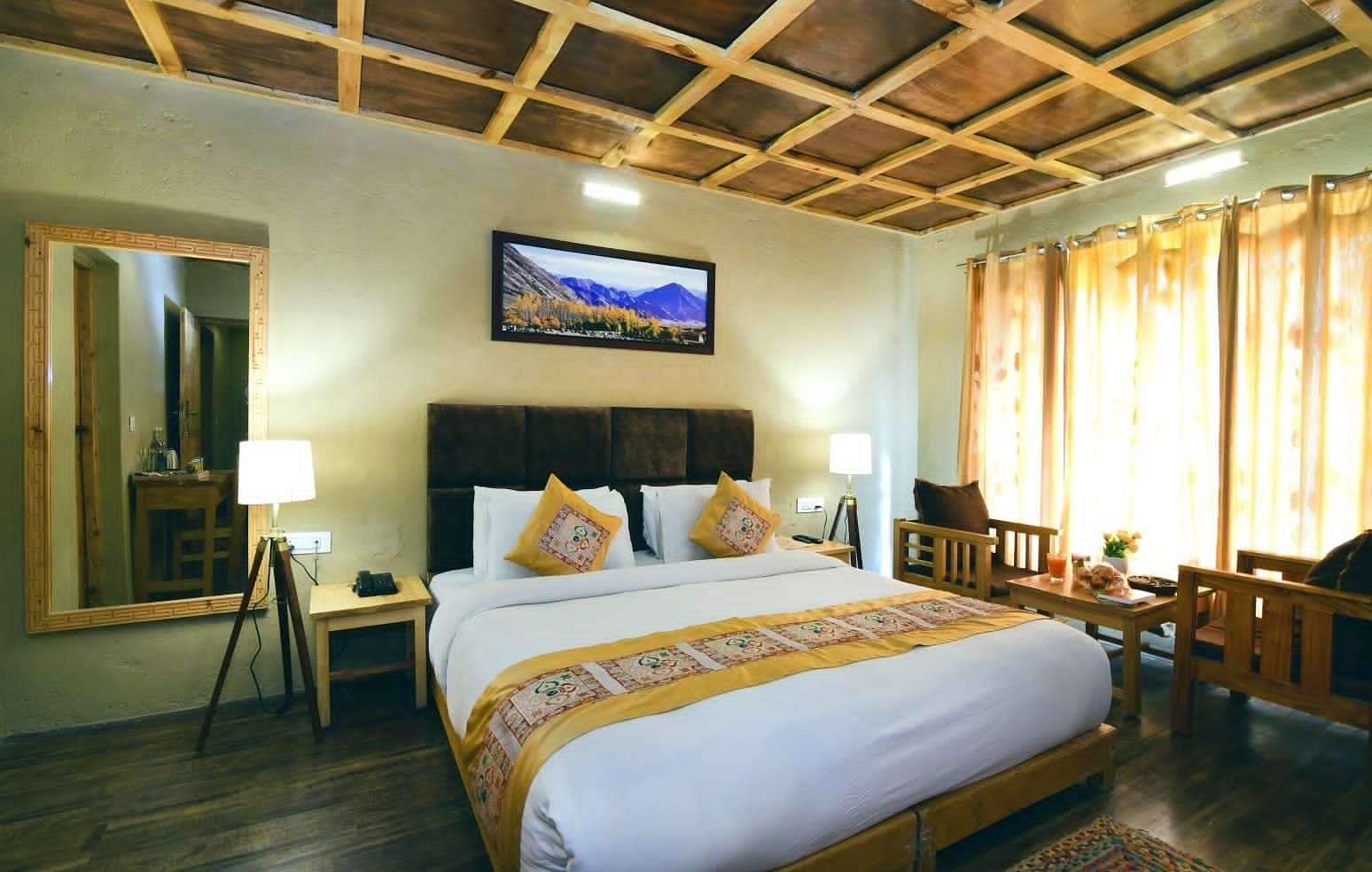 Standard Cottage with a king size bed, a TV, a mirror, and a wooden ceiling at White Sands Resort, Ladakh.