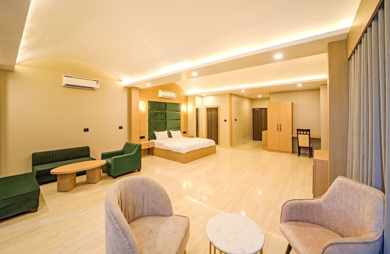 Spacious, well-lit room at Grassfield Riveria Resort, Jaipur, featuring comfortable seating, large bed, and modern amenities.