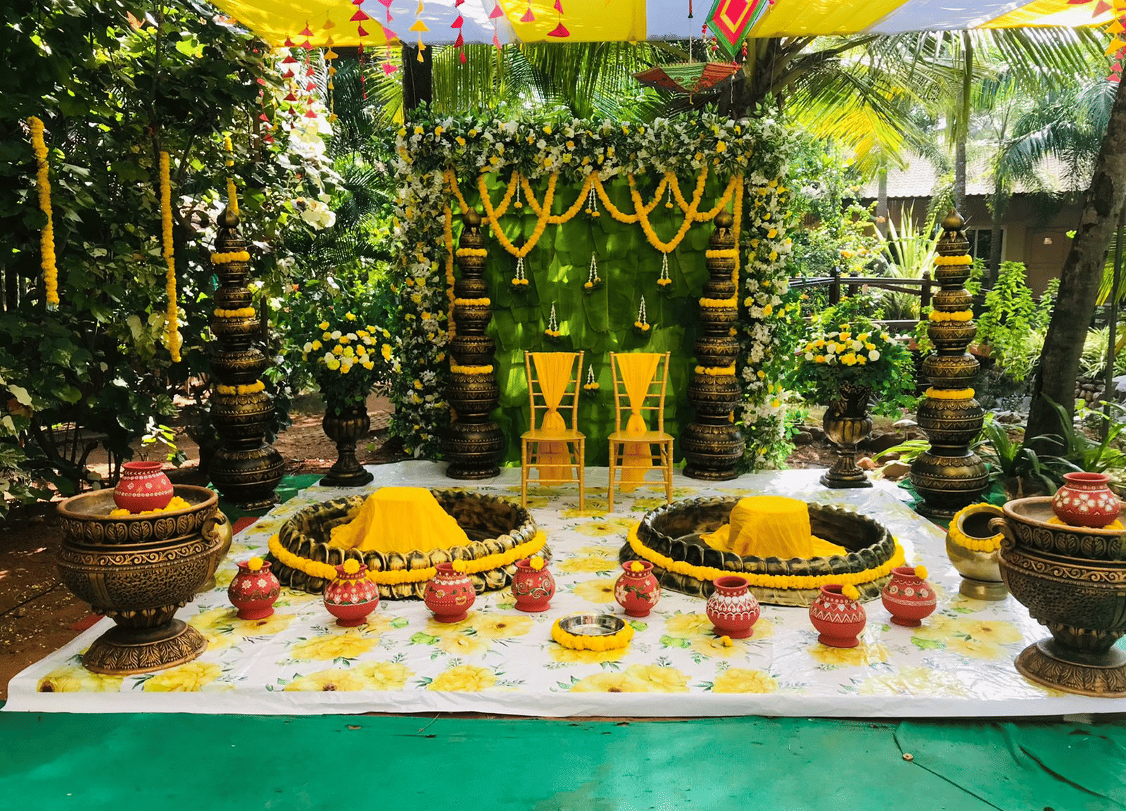 Decorative stage with floral arrangements, brass pots, and colourful backdrop at Paradise Lagoon Resort, Udupi.