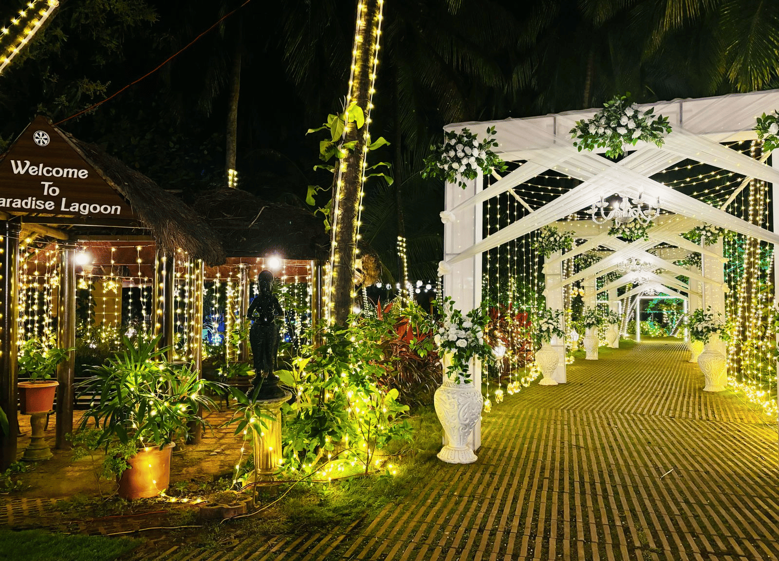 Pathway decorated with lights, flowers, and greenery at Paradise Lagoon Resort, Udupi.
