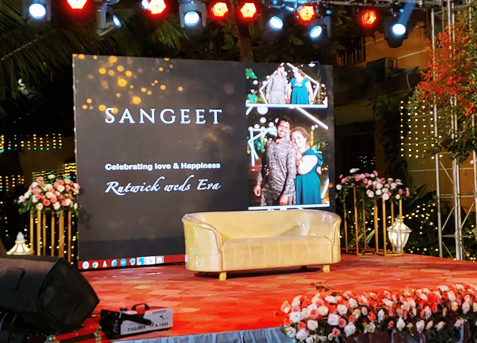 Stage with large digital screen reading 'Sangeet' and floral decor at Paradise Lagoon Resort, Udupi.