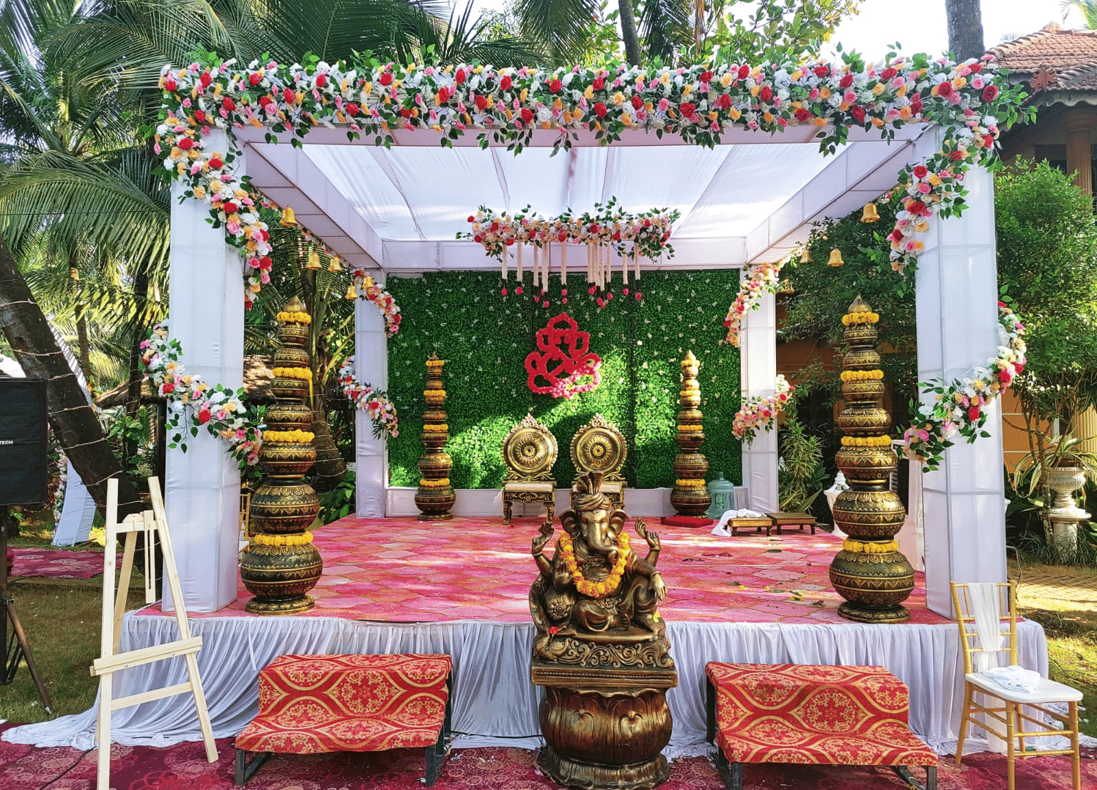 Outdoor wedding stage with floral canopy, and pink seating area at Paradise Lagoon Resort, Udupi.