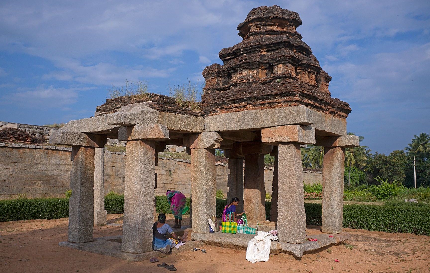 Women relaxing in the shade of an ancient hampi stone Mandapa.