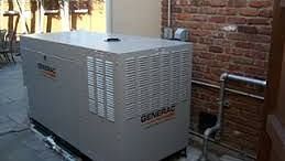 Image of a generator with a brick wall behind.
