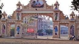 An ornate arched gateway adorned with religious figures and traditional artwork, opening to a temple complex beyond.
