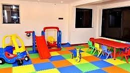 A playroom with colourful mats, toys, and a slide.