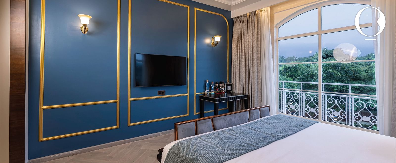 A turquoise coloured wall with golden lines and a wall-mounted television at the Suite at Miros Hotels..