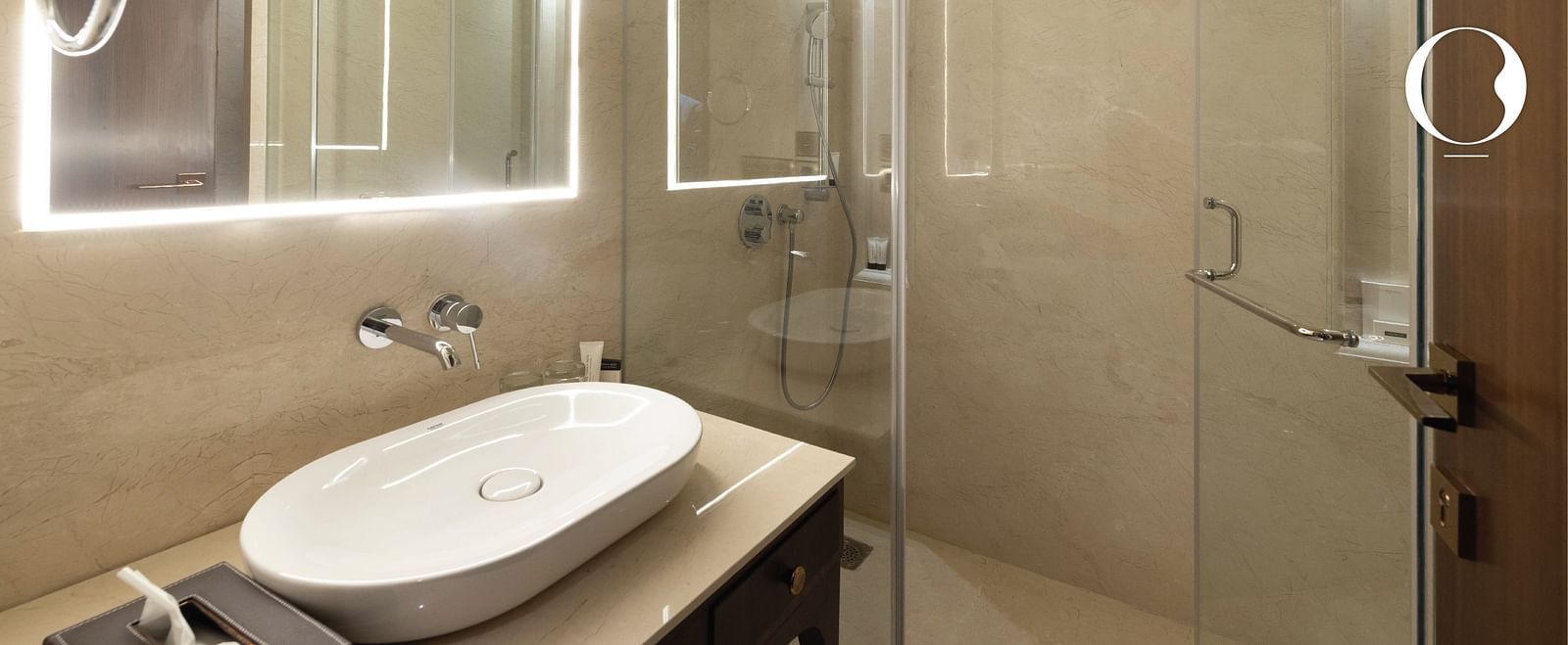 A close up shot of a wash basin with a back lit mirror above it in the bathroom at MIros Hotels.