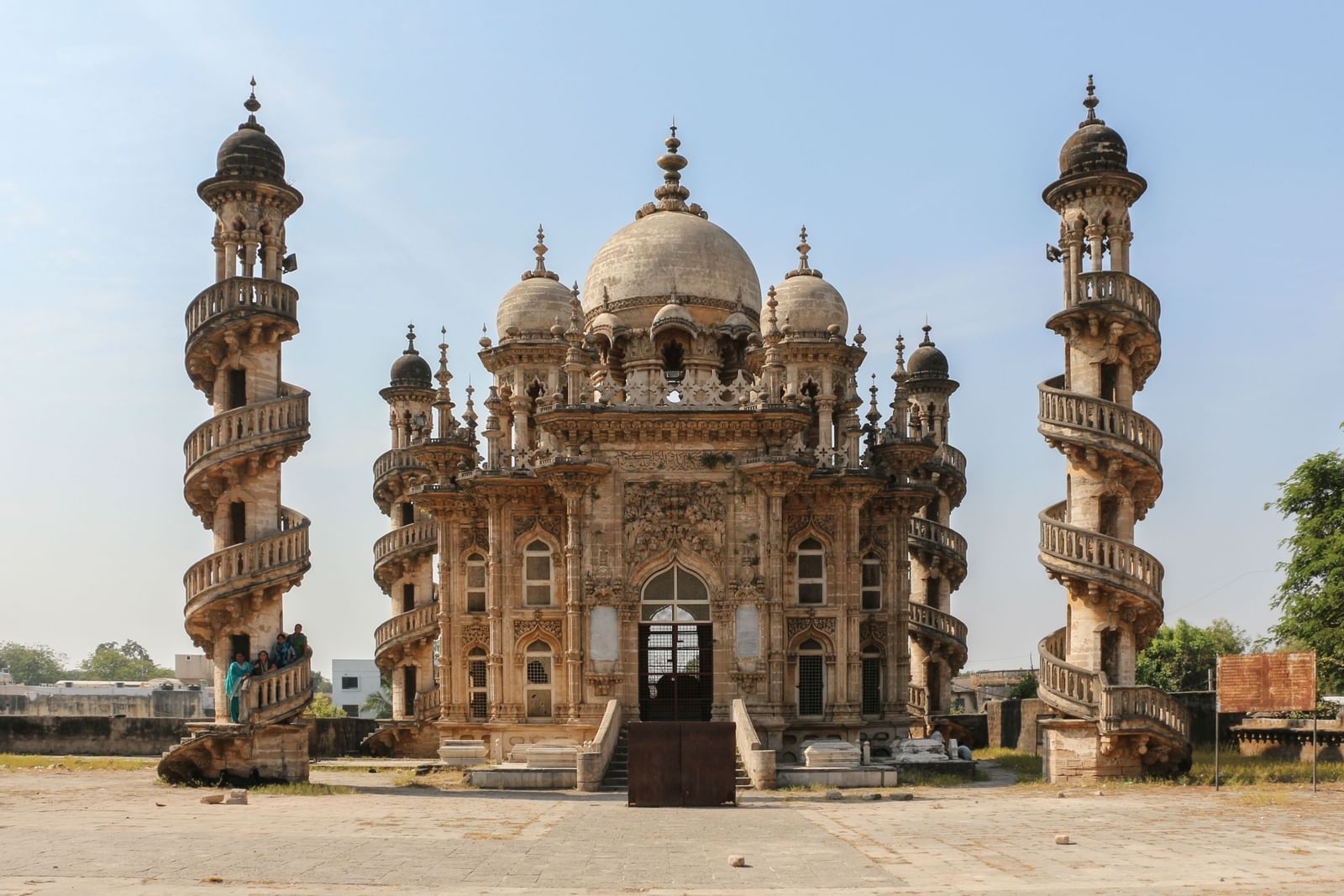 A view of majestic Indo-Islamic mausoleum Mahabat Maqbara with intricate domes and four striking spiral minarets, set against a clear blue sky in Junagadh.