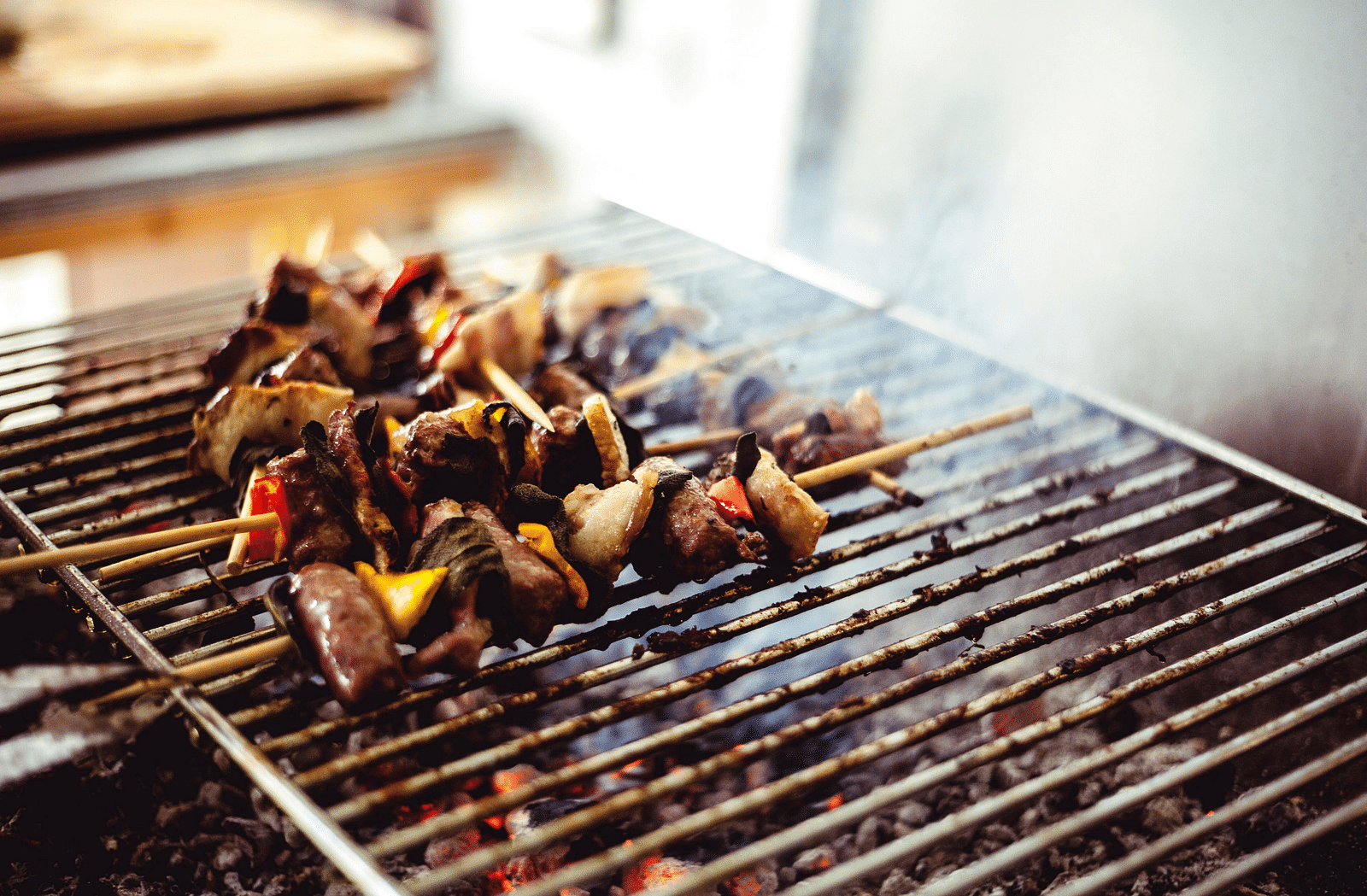 image of a live barbecue stand with a few skewers on the grill emit smoke