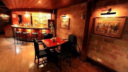 Bar with high chairs and tables, set in a dark theme for guests to savour their drinks.