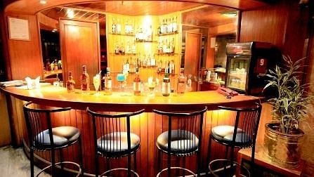 Bar with high chairs and tables, set in a dark theme for guests to savour their drinks.