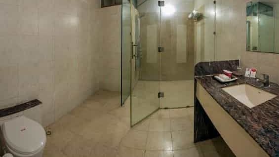 A bathroom featuring a toilet, sink with a patterned counter, and a shower area - Lion Lords Inn Rajula