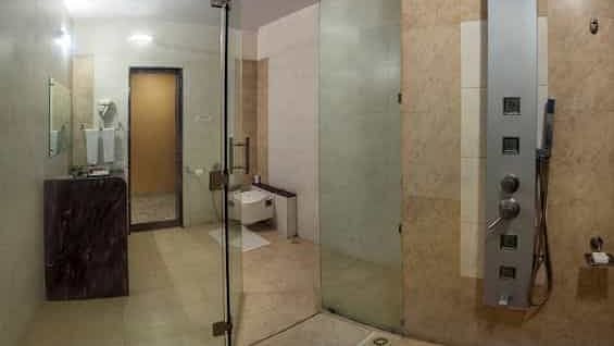 A modern shower cubicle with a rainfall showerhead and multiple body jets - Lion Lords Inn Rajula