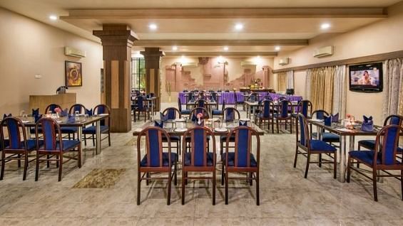 A large dining area is prepared with numerous tables and blue chairs - Lion Lords Inn Rajula