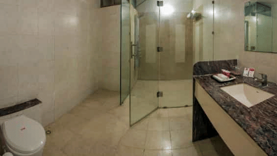 A bathroom featuring a toilet, sink with a patterned counter, and a shower area - Lion Lords Inn Rajula