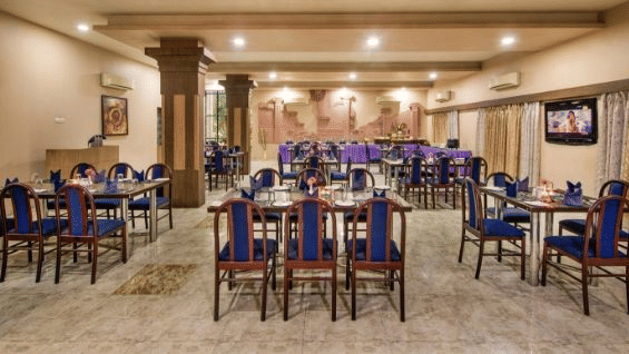 A large dining area is prepared with numerous tables and blue chairs - Lion Lords Inn Rajula